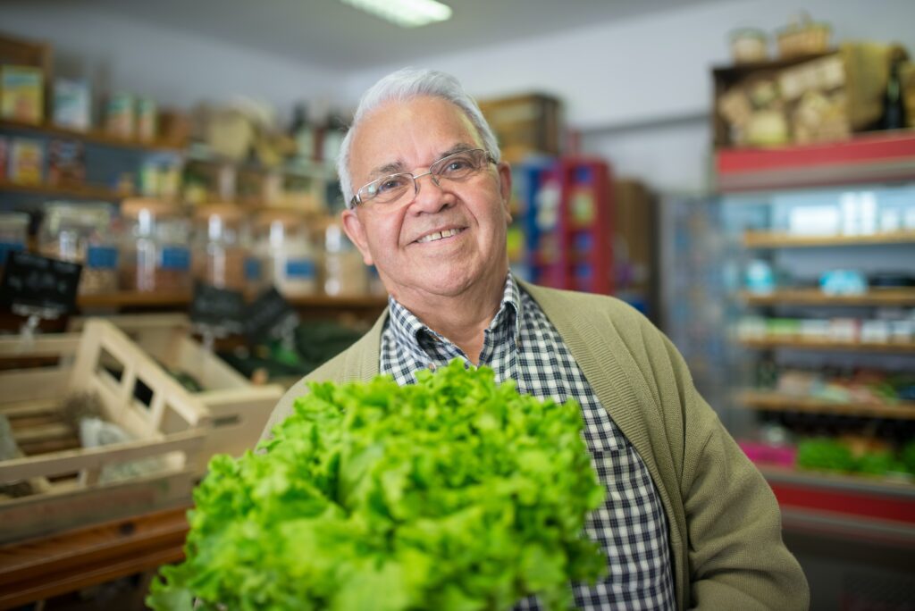 Older man holding lettuce and smiling